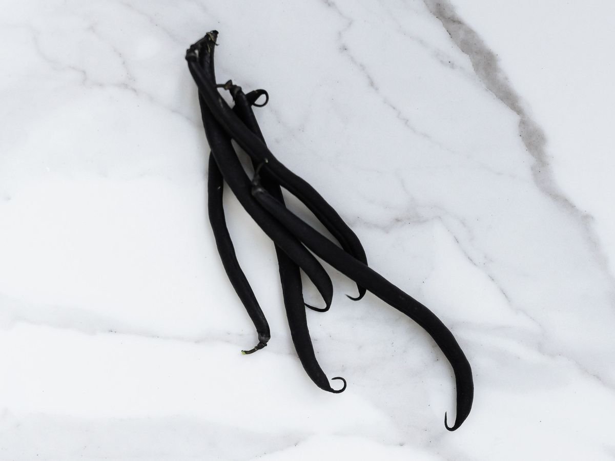A bundle of cured vanilla pods on a pale marble surface